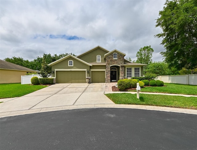 traditional-style house featuring an attached garage, stone siding, fence, concrete driveway, and a front lawn
