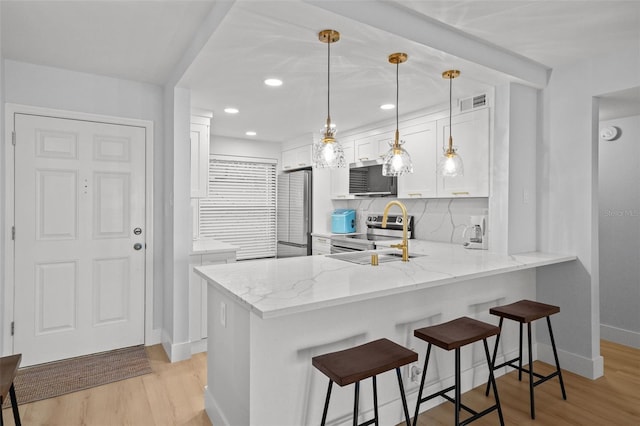 6051 Sun Blvd Unit 111, Saint Petersburg, FL 33715 - kitchen featuring a sink, light wood finished floors, a breakfast bar area, appliances with stainless steel finishes, and a peninsula