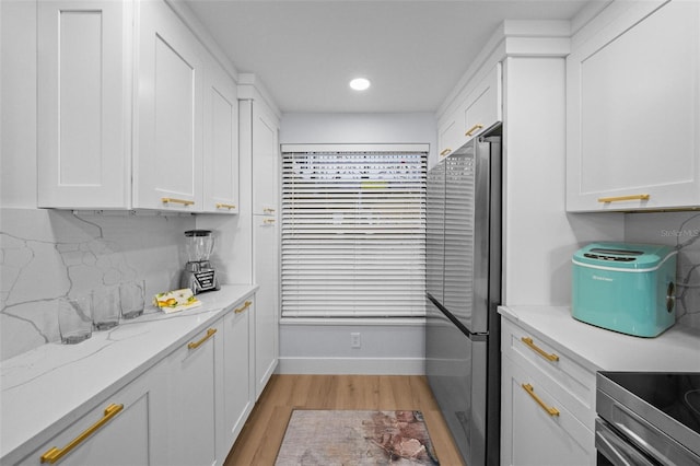 6051 Sun Blvd Unit 111, Saint Petersburg, FL 33715 - kitchen featuring white cabinets, light wood-style flooring, light stone counters, backsplash, and freestanding refrigerator