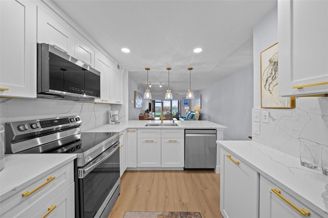 6051 Sun Blvd Unit 111, Saint Petersburg, FL 33715 - kitchen with white cabinetry, stainless steel appliances, backsplash, and a peninsula