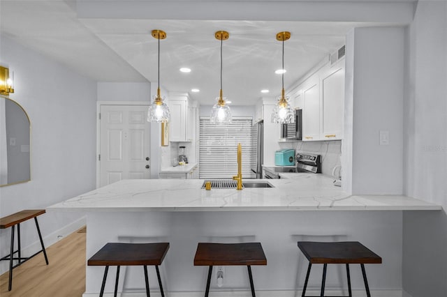 6051 Sun Blvd Unit 111, Saint Petersburg, FL 33715 - kitchen featuring white cabinets, a sink, a peninsula, and decorative backsplash
