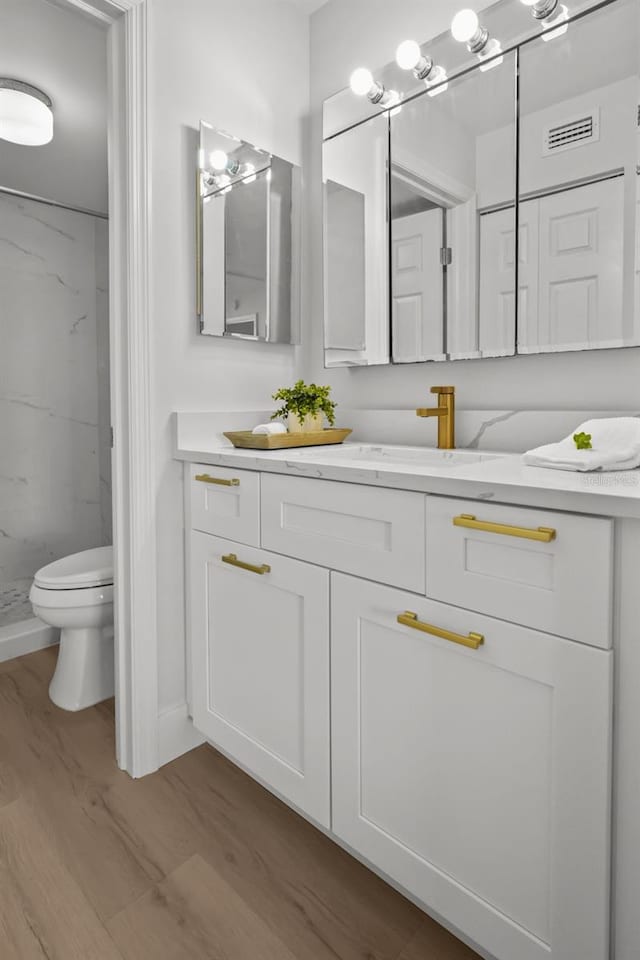 6051 Sun Blvd Unit 111, Saint Petersburg, FL 33715 - full bathroom with vanity, toilet, a stall shower, visible vents, and wood finished floors