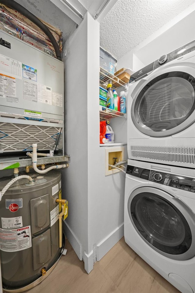 6051 Sun Blvd Unit 111, Saint Petersburg, FL 33715 - laundry room featuring a textured ceiling, baseboards, laundry area, stacked washer and dryer, and electric water heater