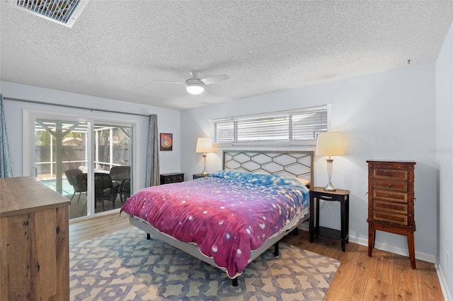 11368 93rd St, Largo, FL 33773 - bedroom with access to outside, light wood-style floors, multiple windows, a ceiling fan, and a textured ceiling