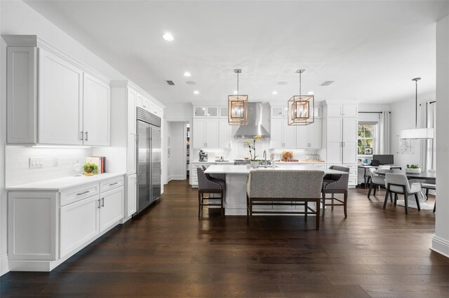 5025 W Homer Ave, Tampa, FL 33629 - kitchen featuring built in refrigerator, wall chimney exhaust hood, recessed lighting, light countertops, and a breakfast bar area