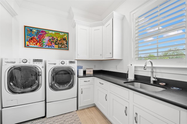 5025 W Homer Ave, Tampa, FL 33629 - clothes washing area featuring a sink, washing machine and clothes dryer, cabinet space, and light wood-style flooring