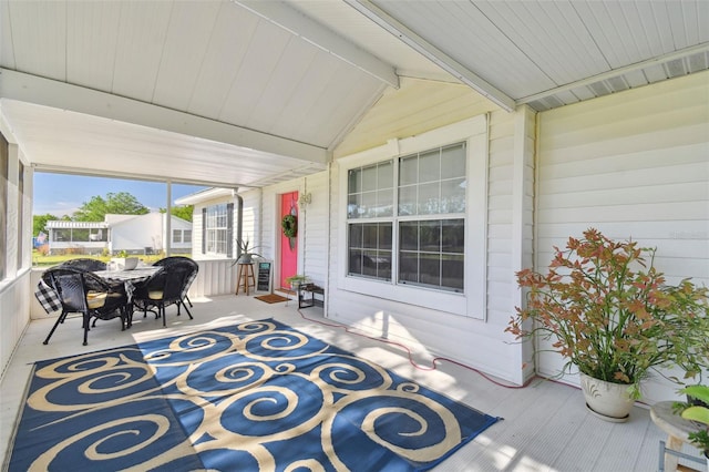 sunroom / solarium featuring outdoor dining area and beam ceiling