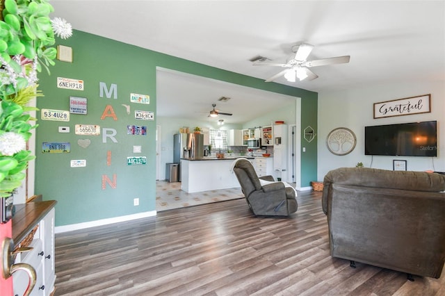 living room featuring a ceiling fan, wood finished floors, lofted ceiling, baseboards, and visible vents