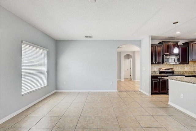 10524 White Peacock Pl, Riverview, FL 33578 - kitchen featuring appliances with stainless steel finishes, arched walkways, backsplash, light stone counters, and pendant lighting