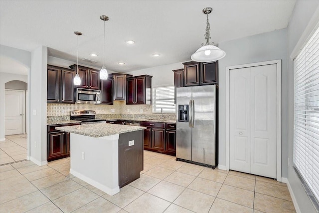 10524 White Peacock Pl, Riverview, FL 33578 - kitchen featuring stainless steel appliances, light tile patterned floors, arched walkways, tasteful backsplash, and a sink