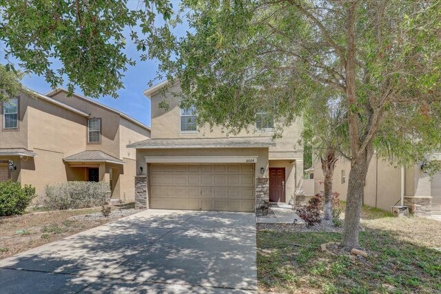 10524 White Peacock Pl, Riverview, FL 33578 - view of front of home featuring stone siding, stucco siding, a garage, and concrete driveway