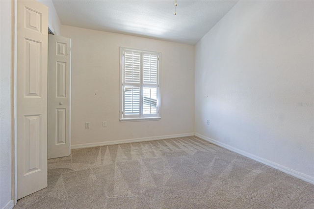 spare room featuring baseboards and light colored carpet