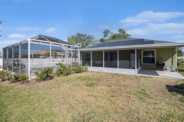 1601 14th St W, Palmetto, FL 34221 - rear view of house featuring roof mounted solar panels, a lawn, a sunroom, and a patio