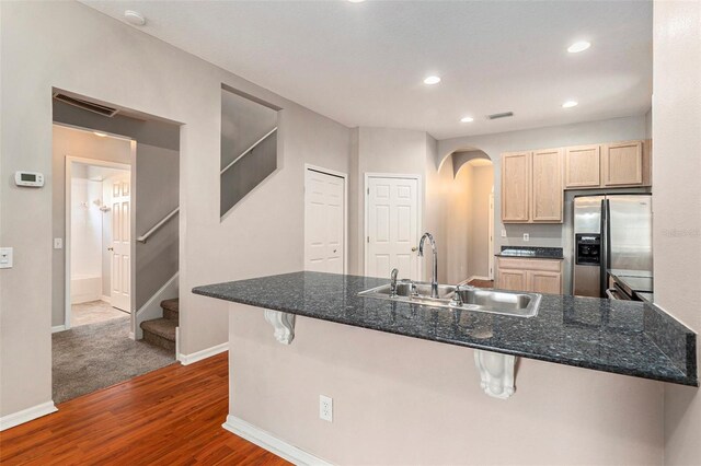 3219 Gianna Way, Land O Lakes, FL 34638 - kitchen with stainless steel refrigerator with ice dispenser, a breakfast bar, light brown cabinetry, dark wood-type flooring, and arched walkways