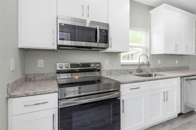 8505 N Brooks St, Tampa, FL 33604 - kitchen featuring appliances with stainless steel finishes, a sink, white cabinetry, light stone counters, and light wood-style flooring