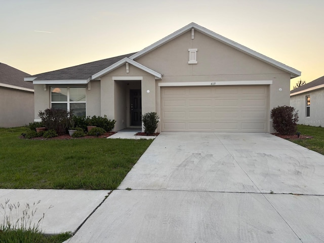 ranch-style home with a front yard, stucco siding, an attached garage, and driveway