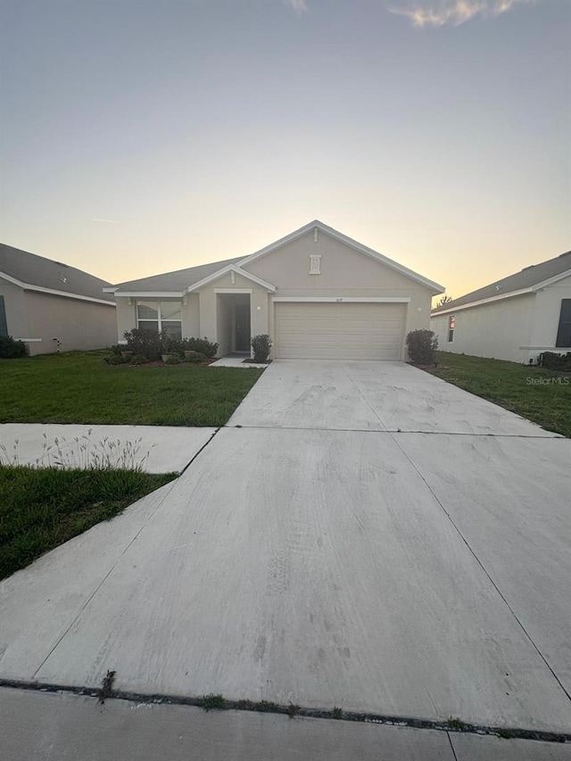 single story home featuring a front yard, concrete driveway, stucco siding, and an attached garage
