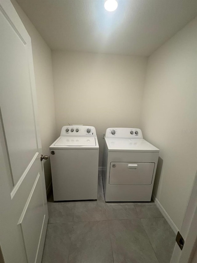 washroom with washing machine and dryer, baseboards, and laundry area
