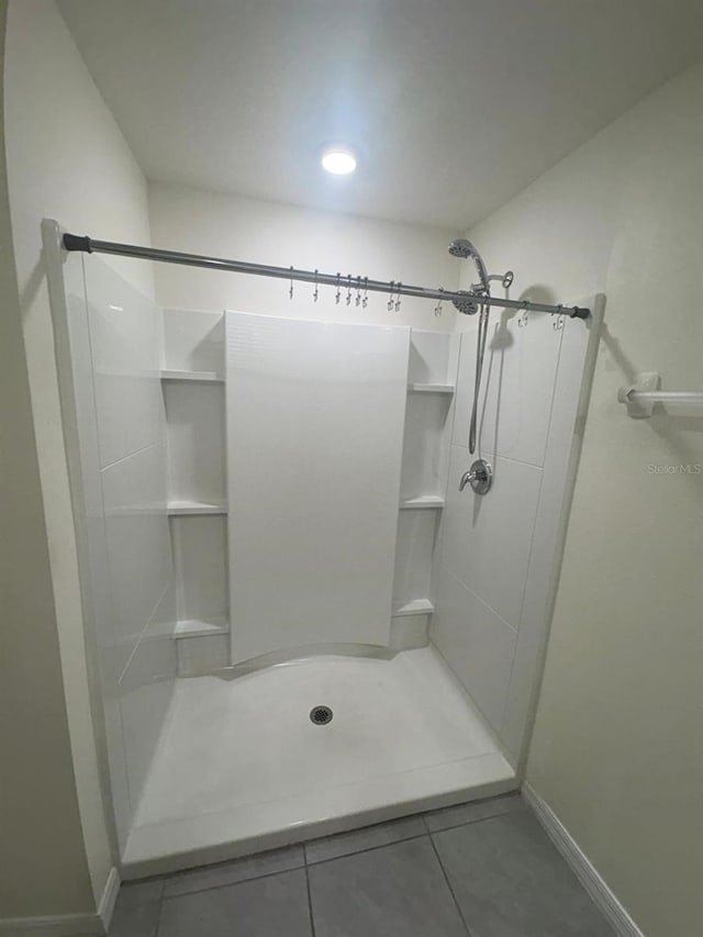 bathroom featuring tile patterned floors, a stall shower, and baseboards