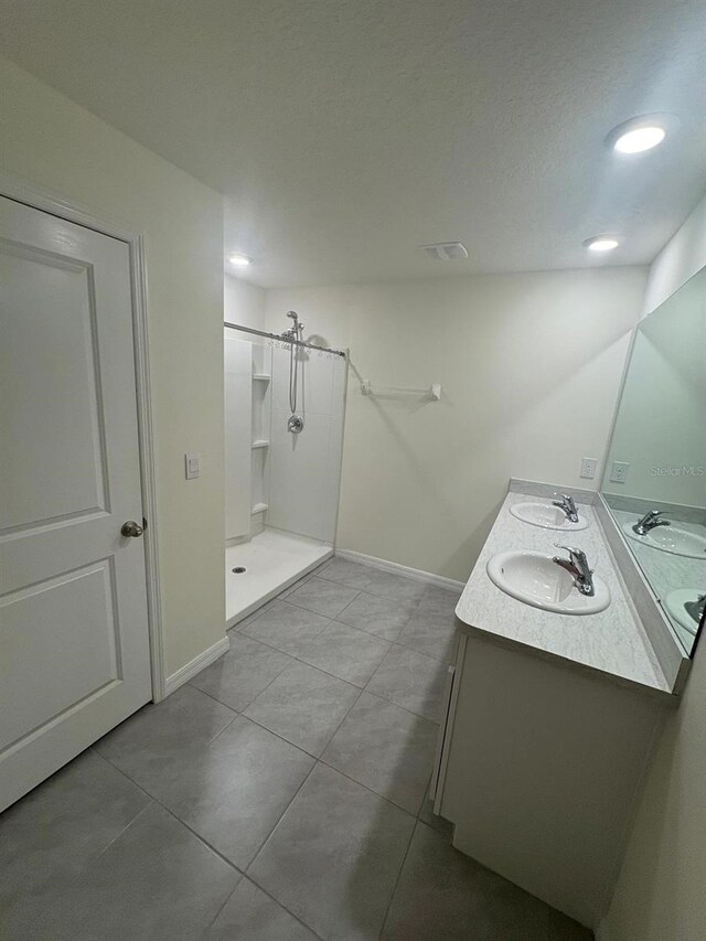 full bathroom featuring double vanity, a sink, and a stall shower
