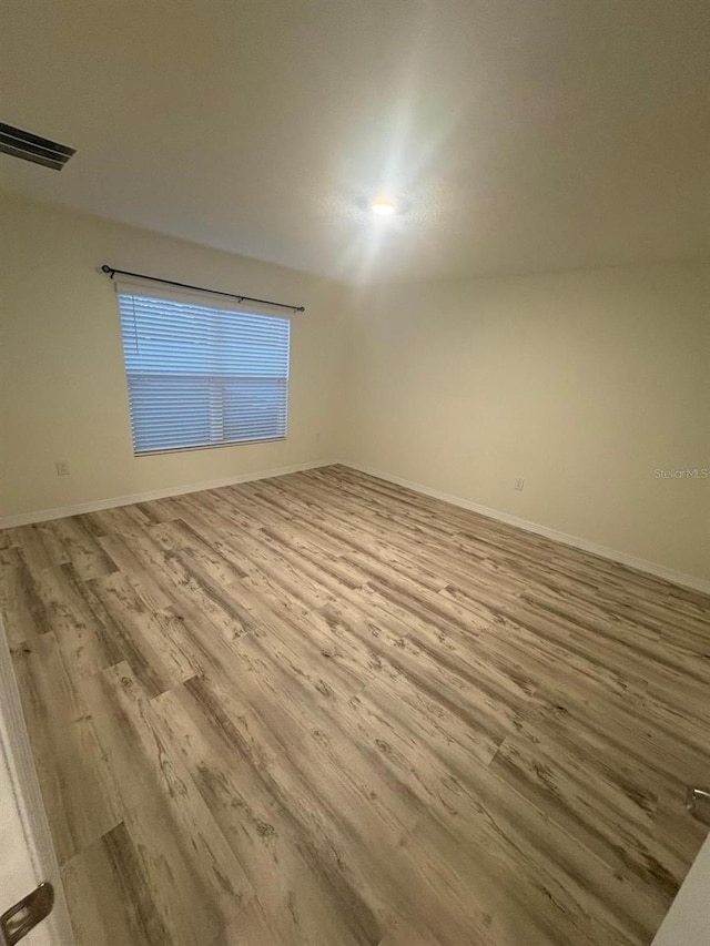 unfurnished room with baseboards, visible vents, and wood finished floors