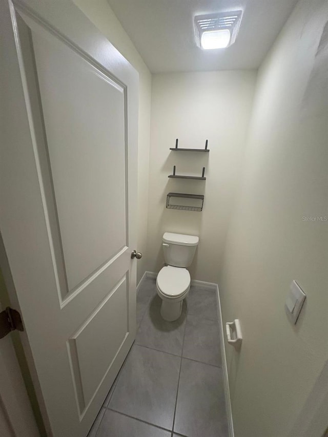 bathroom featuring baseboards, toilet, and tile patterned flooring