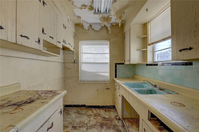 kitchen featuring white cabinets, light countertops, open shelves, a sink, and tasteful backsplash