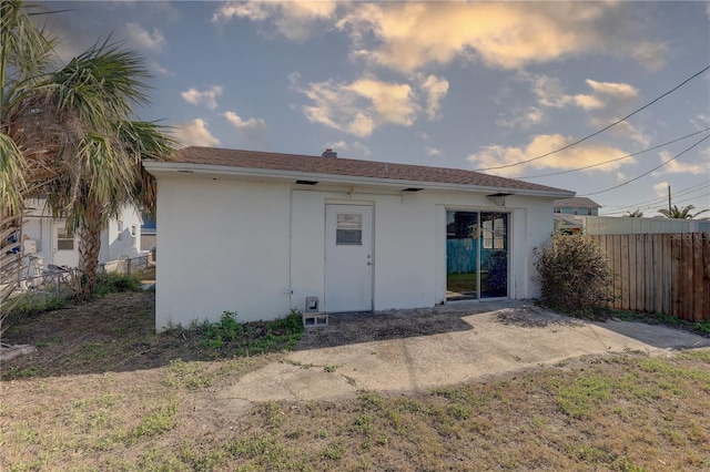 back of house featuring fence and stucco siding