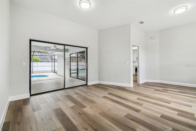 spare room with baseboards, visible vents, and wood finished floors