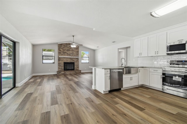 kitchen with vaulted ceiling, a ceiling fan, white cabinetry, open floor plan, and stainless steel appliances