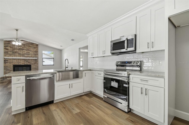 kitchen featuring light wood finished floors, a sink, ceiling fan, and appliances with stainless steel finishes