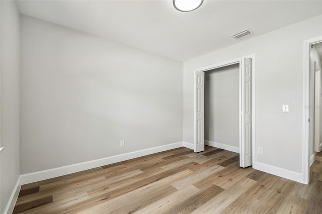 unfurnished bedroom with baseboards, visible vents, a closet, and wood finished floors