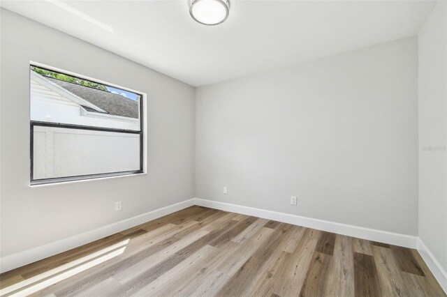 empty room with a skylight, baseboards, and wood finished floors