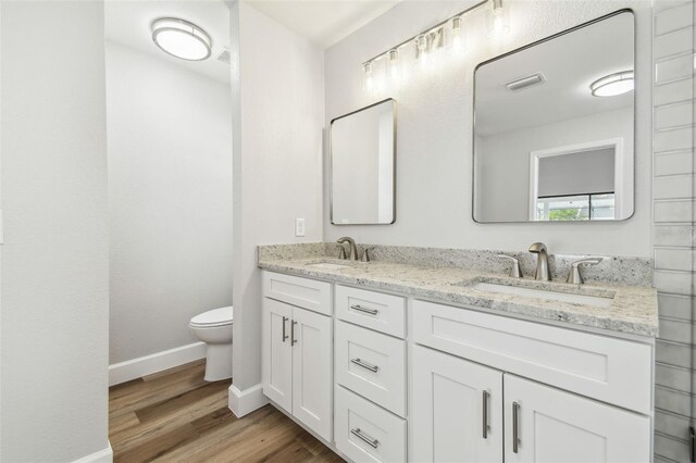 bathroom with visible vents, wood finished floors, toilet, and a sink