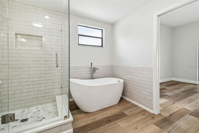 bathroom featuring wood finished floors, a freestanding tub, and a shower stall