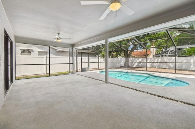 view of swimming pool with ceiling fan, glass enclosure, fence, and a patio area