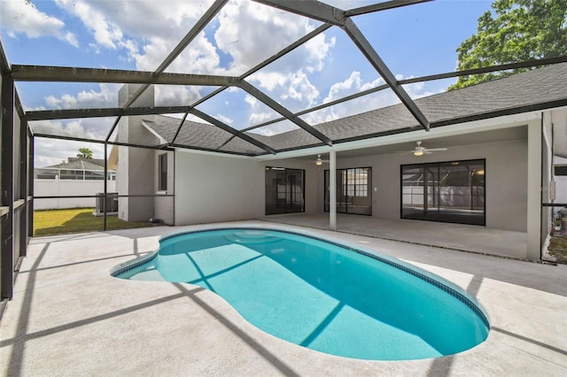 outdoor pool featuring glass enclosure, a patio, and a ceiling fan