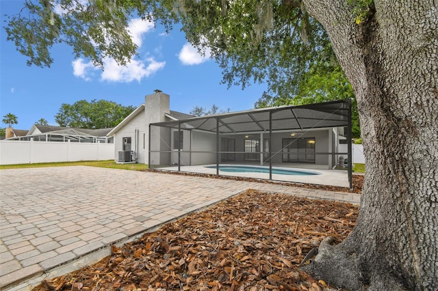 back of property featuring a fenced in pool, a lanai, fence, and a patio area