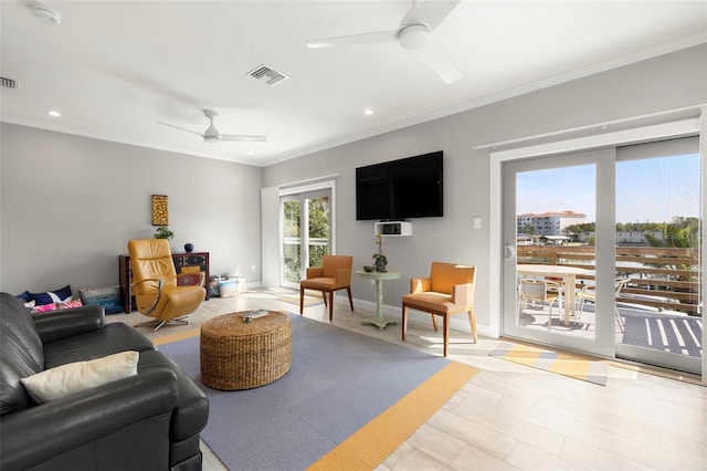 living room featuring baseboards, visible vents, crown molding, and a ceiling fan