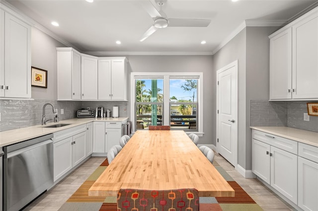 kitchen featuring a sink, a ceiling fan, white cabinetry, stainless steel dishwasher, and ornamental molding