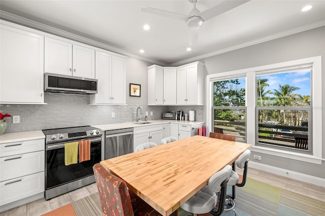 kitchen featuring a sink, stainless steel appliances, crown molding, and tasteful backsplash