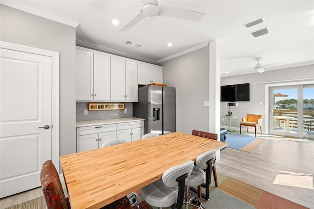 kitchen with light countertops, stainless steel fridge, ornamental molding, decorative backsplash, and ceiling fan