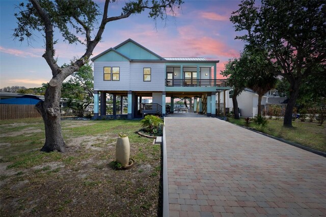 coastal inspired home with stairs, a front yard, decorative driveway, and a carport