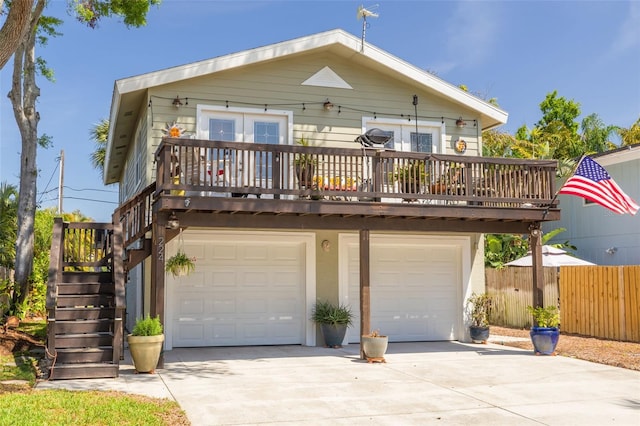 view of front of home with an attached garage, driveway, fence, and stairway