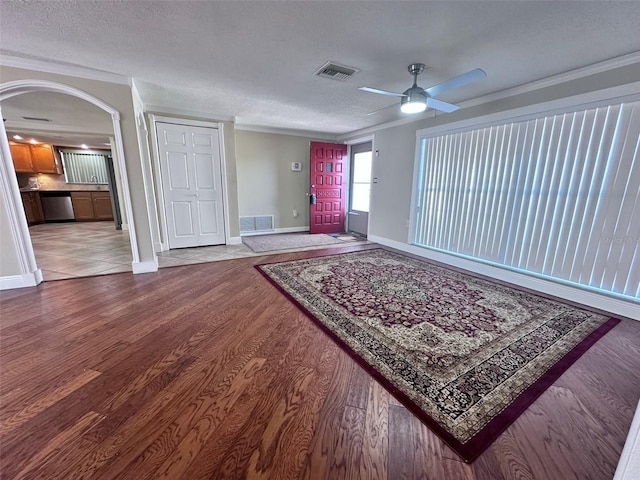 interior space featuring arched walkways, a textured ceiling, visible vents, and wood finished floors