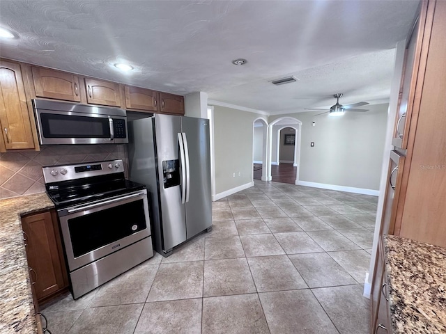 kitchen with tasteful backsplash, stainless steel appliances, arched walkways, ceiling fan, and visible vents