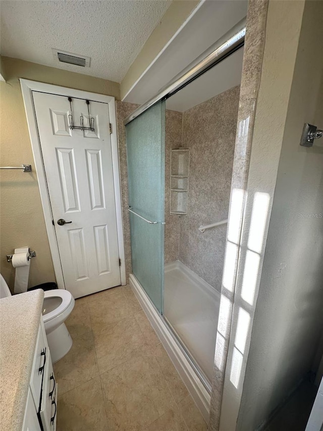 bathroom with a stall shower, visible vents, toilet, and a textured ceiling