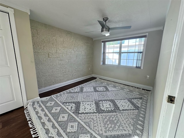 unfurnished room featuring a textured ceiling, crown molding, baseboards, wood finished floors, and a ceiling fan