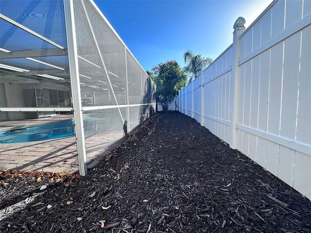 exterior space with a fenced backyard, an outdoor pool, glass enclosure, and a patio