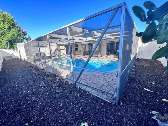 view of swimming pool featuring a fenced backyard, glass enclosure, a patio, and a fenced in pool